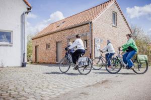 three people riding bikes in front of a brick building at B&B Art.14 in Morkhoven