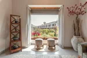 Zimmer mit 2 Stühlen und einem großen Fenster in der Unterkunft Villa Olives, Vanashraya in Jaipur