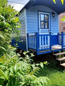 una casa azul con banco y ventana en The Little Blue Caravan en Scy