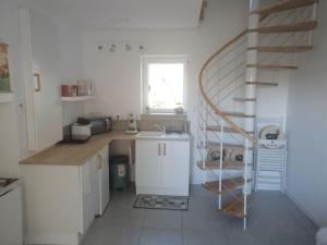 a kitchen with white cabinets and a spiral staircase at L'Embellie un gîte tout confort et cocooning in Villefranche-sur-Saône