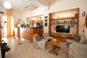 Hotel Villa Gioiosa في ريميني: غرفة معيشة مع تلفزيون وكراسي وطاولة