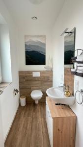 a bathroom with a white toilet and a sink at Idyllisches Ferienhaus in Hatten in Hatten