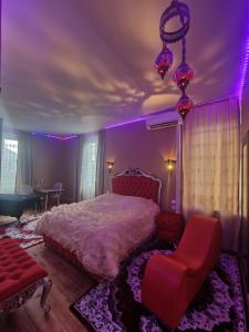 1 dormitorio con cama, silla e iluminación púrpura en Les Spa de Venus suites avec jacuzzi spa privatif, en Charavines