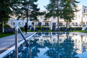 a man walks by a swimming pool in front of a building at Strandhotel Zingst in Zingst