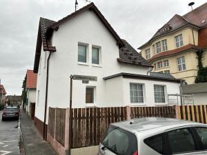 ein weißes Haus mit einem Zaun und einem davor geparkten Auto in der Unterkunft Rona 2xZimmerwohnung in Darmstadt