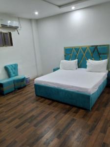 a bedroom with a bed and two blue chairs at Safari Hotel in Lahore