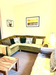 a living room with a green couch and a table at Relaxing Park View Apartment in Hastings