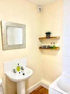 a white bathroom with a sink and a mirror at Relaxing Park View Apartment in Hastings
