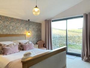 a bedroom with a bed and a large window at Sheepfold Barn in Penruddock