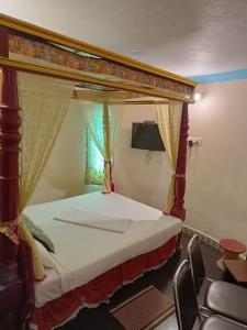 a bedroom with a canopy bed and a chair at Kottai Veedu Pondicherry in Pondicherry