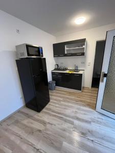 eine Küche mit einem schwarzen Kühlschrank im Zimmer in der Unterkunft Rona 2xZimmerwohnung in Darmstadt