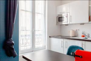 kuchnia z białymi szafkami, stołem i kuchenką mikrofalową w obiekcie Le Studio Versaillais w Wersalu