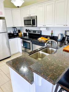 a kitchen with white cabinets and a stainless steel sink at The Gables of PEI in Stanley Bridge