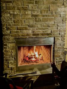 a brick fireplace with a fire in it at The Gables of PEI in Stanley Bridge