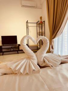 dos cisnes están sentados en la parte superior de una cama en Nilai Youth City Residence en Nilai
