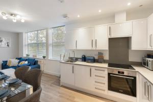 a kitchen with white cabinets and a living room at Cosy Retreat in the Heart of Golders Green in London