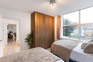 1 dormitorio con 2 camas y ventana grande en Cosy Retreat in the Heart of Golders Green, en Londres