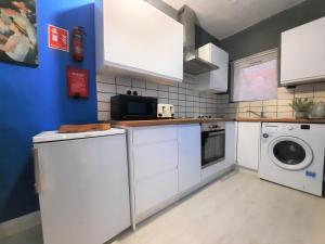 a kitchen with white cabinets and a washer and dryer at 3-Bed House in Colchester with Parking and WiFi in Colchester