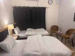 伊斯蘭堡的住宿－Stay Inn Guest House，一间设有两张床、椅子和时钟的房间