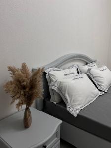 1 cama con almohadas blancas y un jarrón sobre una mesa en 2х комнатная квартира с кодовым замком en Uralsk