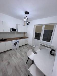 uma cozinha branca com uma mesa, uma mesa e cadeiras em 2х комнатная квартира с кодовым замком em Uralsk