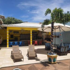 - un ensemble de chaises et d'un parasol sur la terrasse dans l'établissement Casa nova, piscina, área gourmet e muito conforto., à Iguaba Grande