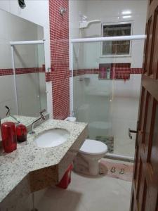 La salle de bains est pourvue de toilettes, d'un lavabo et d'une douche. dans l'établissement Casa nova, piscina, área gourmet e muito conforto., à Iguaba Grande
