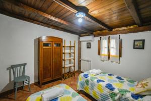 um quarto com uma cama e uma cadeira e um tecto de madeira em Villa Cusidore em Oliena