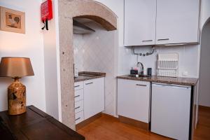 cocina con armarios blancos y mesa con lámpara en Casa do Briamante 6, en Sintra