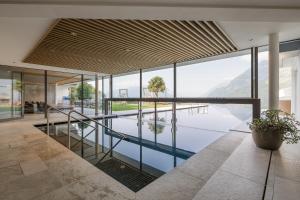 a house with a swimming pool and glass walls at Apartmenthaus Gruberhof in Schenna