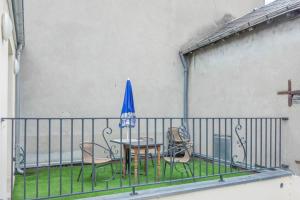 a table and chairs with a blue umbrella on a balcony at Les Augustins *T4* in Orléans