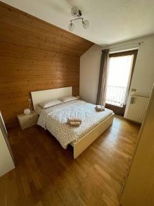 1 dormitorio con 1 cama y pared de madera en Suan Hut en Ziano di Fiemme