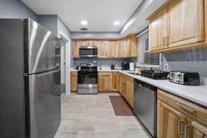uma cozinha com armários de madeira e um frigorífico de aço inoxidável em Elegant Oasis 4 Bedroom Home Away from Home em Utica