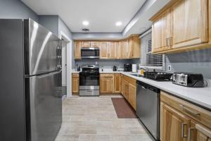 a kitchen with wooden cabinets and a stainless steel refrigerator at Elegant Oasis 4 Bedroom Home Away from Home in Utica