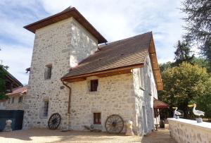un gran edificio de piedra con techo de madera en La Tour de Coron, en Belley