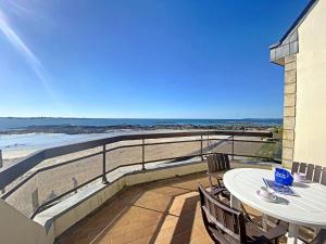 a balcony with a table and chairs and the beach at RÉF 318 - LARMOR-PLAGE spacieux type 3 pleine vue mer avec terrasse, ascenseur, parking in Larmor-Plage