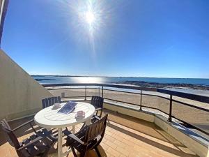 a balcony with a table and chairs and the beach at RÉF 318 - LARMOR-PLAGE spacieux type 3 pleine vue mer avec terrasse, ascenseur, parking in Larmor-Plage