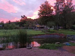 un estanque en un campo con una puesta de sol en el fondo en Haus Rothenberg en Nohfelden
