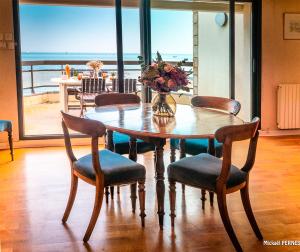 a table with chairs and a vase of flowers on it at RÉF 318 - LARMOR-PLAGE spacieux type 3 pleine vue mer avec terrasse, ascenseur, parking in Larmor-Plage
