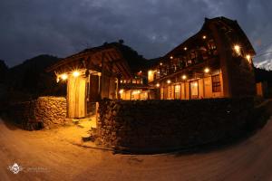 un edificio de madera con luces encendidas por la noche en Dinh Đá H'Mông - Karsterly Rock Lodge en Dồng Văn