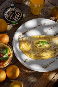 a white plate with an omelet on a table with oranges at Riad N'S & Spa in Marrakesh