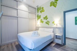 um quarto com uma cama branca e toalhas em IVY HOUSE em Sevilha