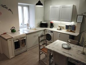 a kitchen with a washing machine and a table at The Enchanted Cottage in Taizé