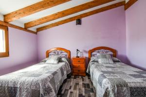 two beds in a room with purple walls and wooden beams at aCienLeguas in Castrojeriz