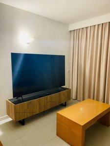 ein Wohnzimmer mit einem großen TV und einem Tisch in der Unterkunft Newly refurbished 2 bed appt Vilamoura in Vilamoura