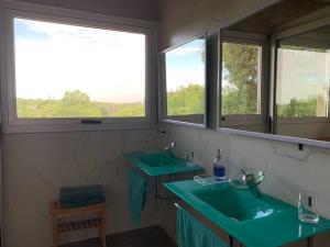 een badkamer met 2 groene wastafels en 2 ramen bij Cabaña La Reserva Suite in La Granja