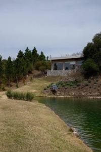 a house on a hill next to a body of water at Cabaña La Reserva Suite in La Granja