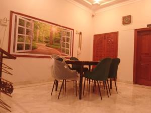 a dining room with a table and chairs and a painting at Travel lodge clifton in Karachi