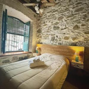 a bedroom with a large bed with a stone wall at Posada San Gabriel in Colonia del Sacramento