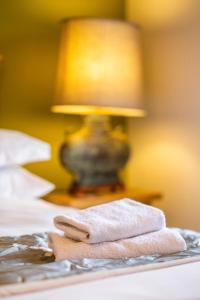 a pile of towels on a bed with a lamp at Errichel House and Cottages in Aberfeldy +119 photos